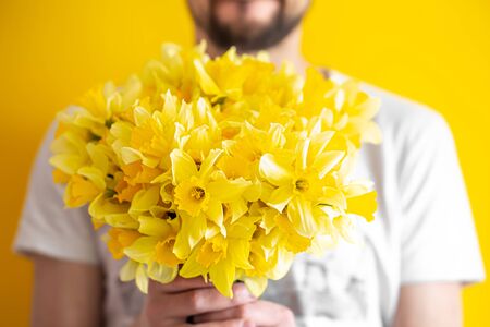 Hipster man on a yellow background in a shirt and a bouquet of flowers.の写真素材
