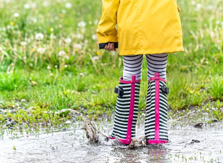 A child in rubber boots jumps in a puddle. Close up. Autumn-summer conceptの写真素材