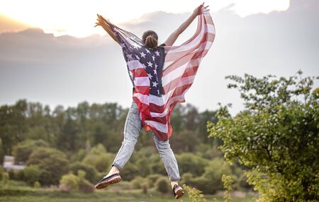 America's Day. A young woman in nature with an American flag. Patriotism and love.の写真素材