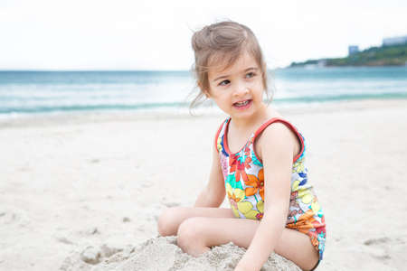 Little cute girl playing in the sand on the beach by the sea. Summer entertainment and recreation.の写真素材