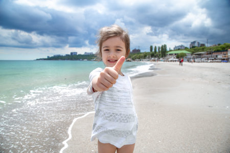 A little cute girl runs on a Sunny day on the beach by the sea. Recreation and nature.