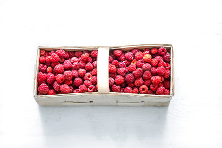 Beautiful basket with fresh raspberries on a light wooden background. The concept of healthy eating.