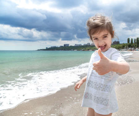 A little cute girl runs on a Sunny day on the beach by the sea. Recreation and nature.の写真素材