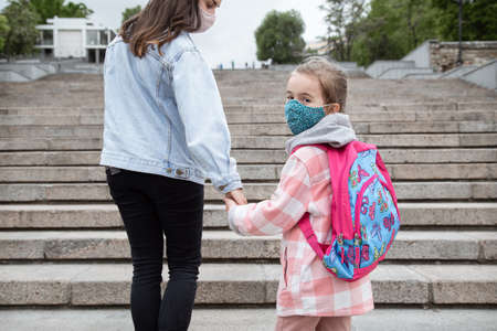 Back to school. Coronavirus pandemic children go to school in masks. Friendly relations with my mother.の写真素材