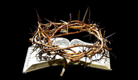 The crown of thorns lies on the open book of the Bible. Objects on an isolated black background. The concept of Holy week.の写真素材