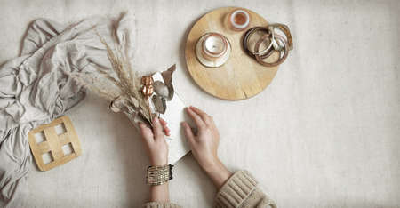 Female hands hold dried flowers on white background with wooden decor details, copy space and top viewの写真素材