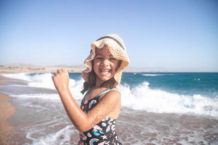 Portrait of a cheerful little girl in a bathing suit by the sea on a Sunny day.の写真素材