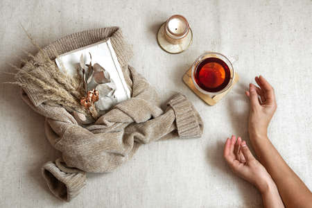 Still life with female hands, a cup of tea and dried flowers on a warm sweater, the concept of autumn comfort top viewの写真素材