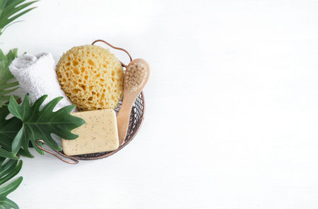 Still life of bath accessories. In a basket a washcloth, a soap, brush, a towel on a white background copy space, top view.の写真素材