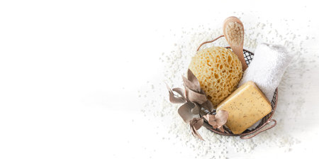 Still life of bath accessories. In a basket a washcloth, a soap brush, a towel, scattered white sea...