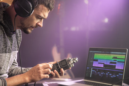 Professional headphones connected to music mixer and laptop on blurred background of music studio with studio light close up.の写真素材