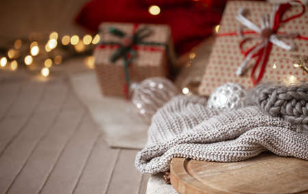 Christmas background with knitted sweater in focus on blurred background of christmas decorations and wrapped gifts copy space.の写真素材