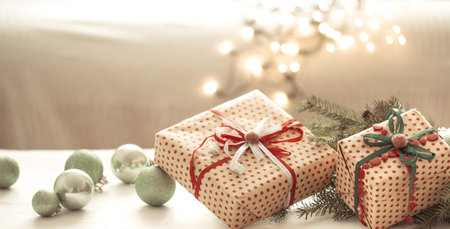 Close up of beautifully wrapped christmas gifts on blurred background of cozy interior copy space.