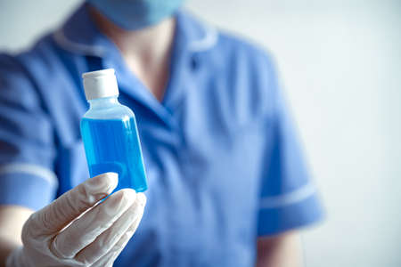 The doctor in white gloves holds in hands hand sanitizer close up. Personal hygiene and virus protection concept.の写真素材