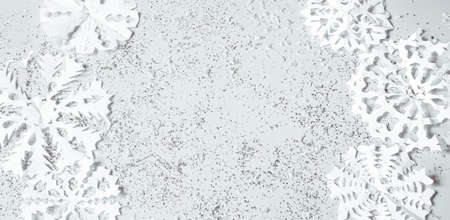 Light background with hand-cut paper snowflakes and sequins in a plane. Christmas banner concept.の写真素材