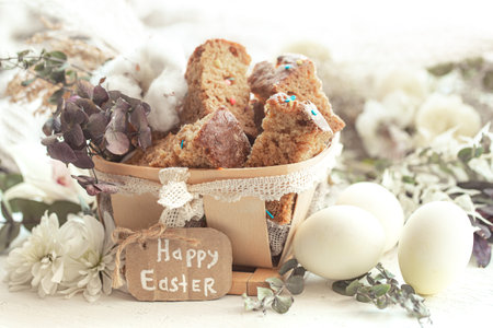 Easter still life with pieces of festive cupcake, eggs and flowers on a blurred light background....