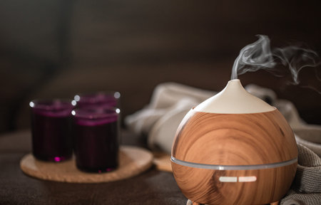 Oil diffuser on blurred background wirh decor elements. Aromatherapy and health care concept.