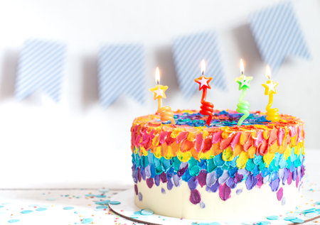 Multi-colored birthday cake decorated with cream and candles. Birthday party concept.の写真素材