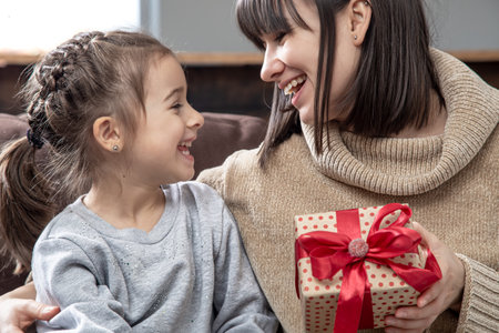 Happy young mom with her cute daughter. The concept of congratulations on the holiday, family relationships and quality time together.の写真素材