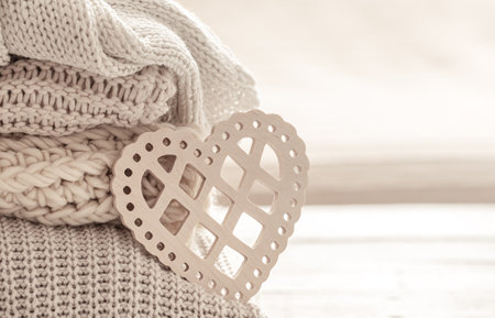 Composition with a decorative heart on the background of neatly folded warm clothes. Valentine's day concept.の写真素材