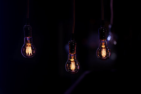 Three luminous lamps hang in the dark from the boke. Decor and atmosphere concept.の写真素材