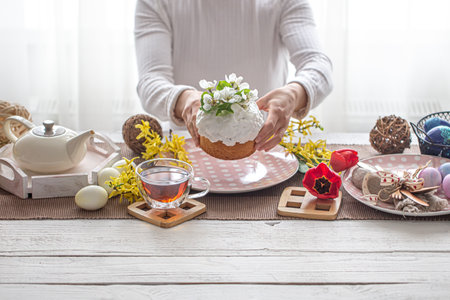 Easter composition with cake in female hands, tea, flowers, eggs and decor details. Easter family holiday concept.の写真素材