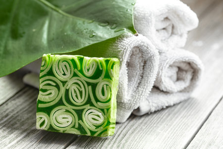 Spa composition with a bar of handmade soap, towels and a large leaf. Health and beauty concept.の写真素材