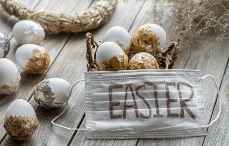 Decorated Easter eggs and a white medical mask with the inscription Easter. The concept of celebrating Easter in a pandemic.の写真素材