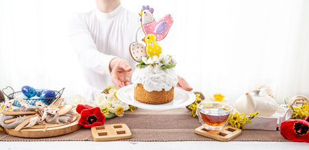 Women's hands are holding a festive Easter cake, decorated with flowers and bright details.
