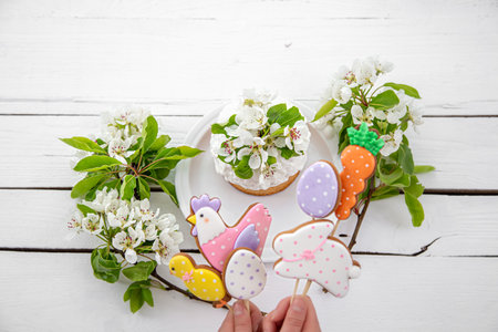 Close-up of bright Easter gingerbread cookies on sticks and Easter cake decorated with flowers. The concept of decor for the Easter holiday.の写真素材