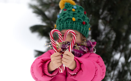 Happy child with a big candy canes under a christmas tree. Winter holidays concept.の写真素材