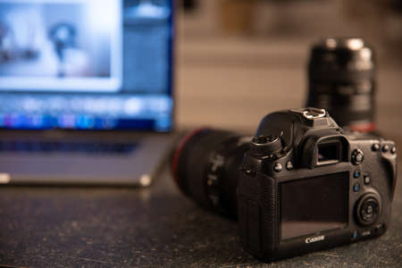 Professional camera on a blurred background with a laptop. The concept of working with photos and videos.の写真素材