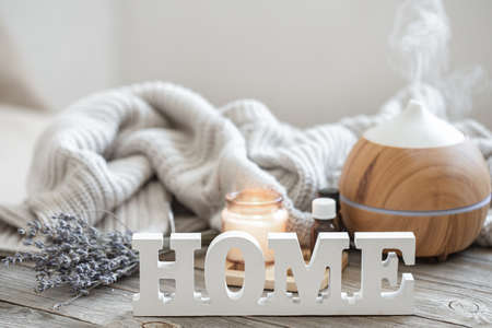 Aroma composition with modern aroma oil diffuser on wooden surface with knitted element, oils and candle on blurred background.の写真素材