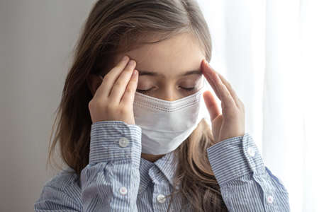 Portrait of a elementary school girl in a protective disposable mask. Childhood concept during pandemic and quarantine.の写真素材