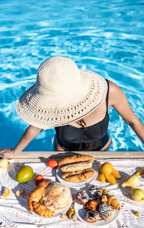 Young woman rejoices at delicious food near the pool. The concept of vacation and recreation in a...