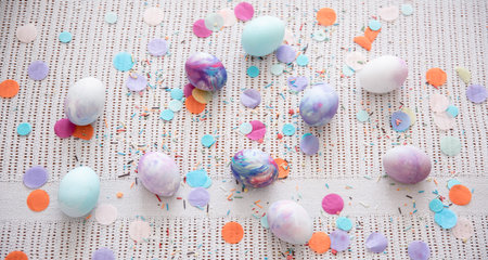 Painted Easter eggs among colored confetti. Easter holiday concept.