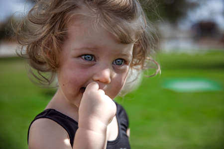 Little curly girl in the summer outdoors close-up on blurred background.の写真素材