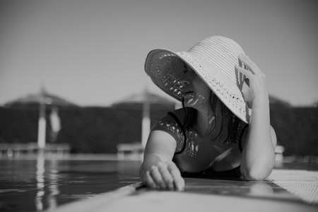 Attractive girl resting in the sun wearing a straw hat. Vacation and recreation concept. Black and white photo.の写真素材