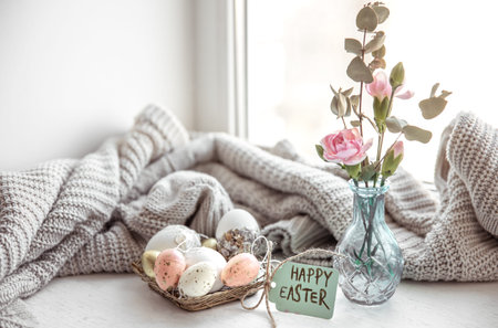 Easter still life with Easter eggs, fresh flowers in a vase and the inscription Happy Easter on the...