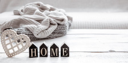 Still life in hygge style with wooden word home and knitted element. The concept of home comfort and...