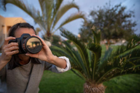 The girl makes a photo on a professional SLR camera outdoors in nature close up.の写真素材