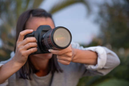 Close up young woman taking pictures outdoors on a professional SLR camera.の写真素材