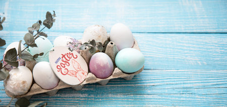 Close up of a tray with festive Easter eggs on a wooden surface copy space. Happy Easter concept.