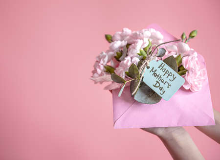 Festive composition with an envelope with fresh flowers and the inscription Happy Mother's Day flat lay.の写真素材