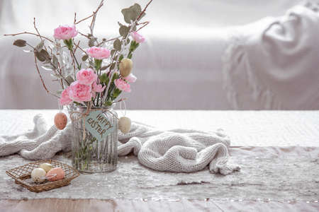 Still life with fresh flowers in a vase and details of festive Easter decor on a blurred background.の写真素材