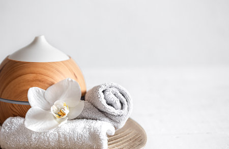 Close up of air humidifier, towel and orchid flower. Aromatherapy and care and health concept.の写真素材