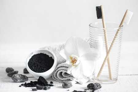 Still life with organic bamboo brushes and activated carbon powder and an orchid flower as a decorative element. Oral hygiene and dental care.の写真素材