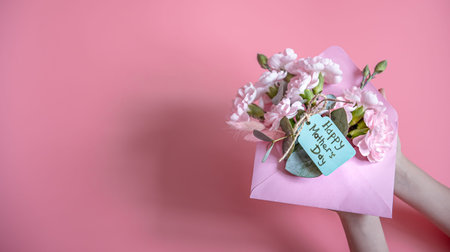 Festive composition with an envelope with fresh flowers and the inscription Happy Mother's Day flat lay.の写真素材