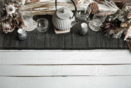 Home composition with teapot, glasses and many decorative details on a wooden table.の写真素材