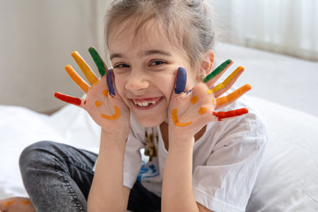 Cheerful little girl with palms painted with smiles. Children's creativity and art.の写真素材